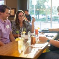 Two women and one man sitting at table and chatting